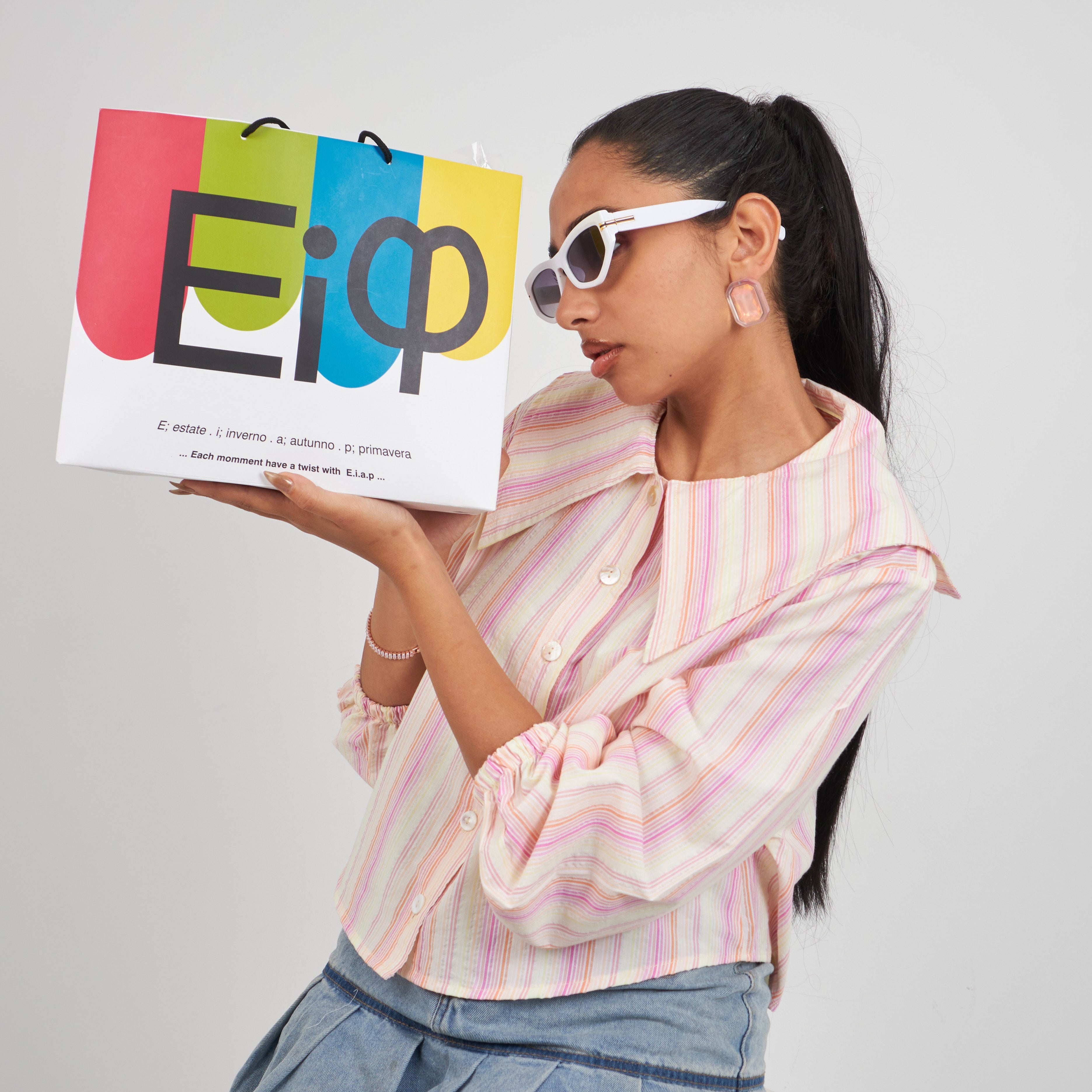 Woman holding a colorful shopping bag with 'Elap' branding against a plain background